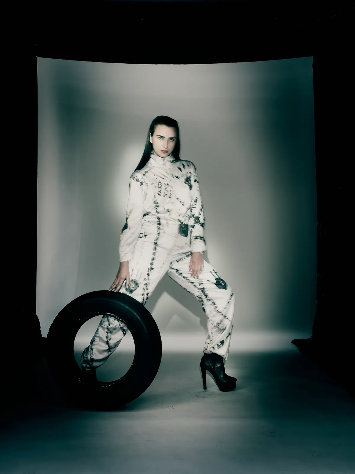 Look 1 of Driven by Instinct — model seated on a tyre in a white tyre-printed jumpsuit