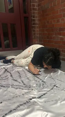 Nelliza rolling a painted tyre across fabric on the ground