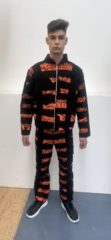 Model wearing orange and black printed jacket and trousers
