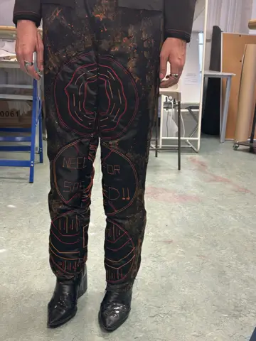 Model fitting the dark printed jacket and trousers